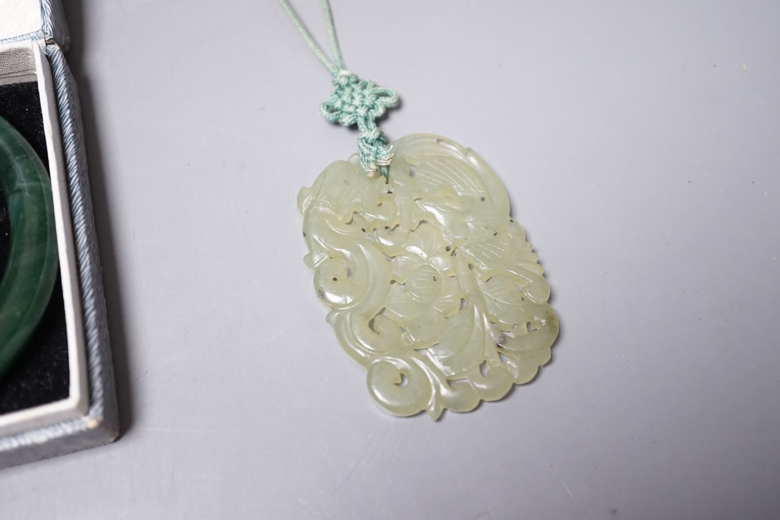 A Chinese carved bowenite jade pendant, a pair of green paste earrings and a green paste bangle.